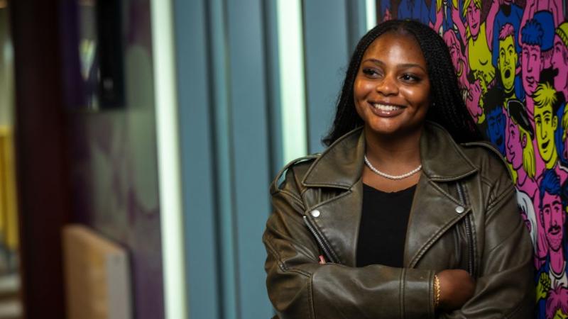 female student standing smiling to camera with arms folded